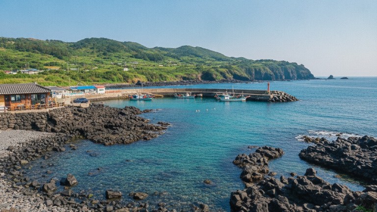 韓国・済州島 西帰浦の港と火山岩、漁船が浮かぶ青い海岸の海