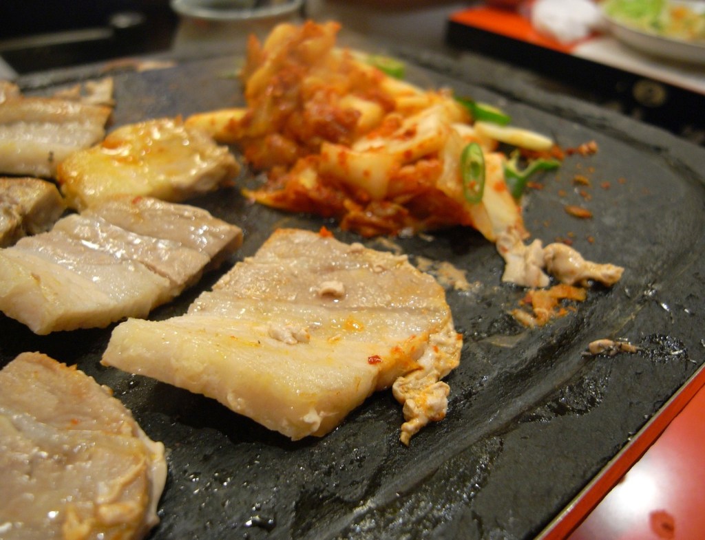 A busy Korean BBQ restaurant table with side dishes, grill, and shared plates — korean bbq sejong