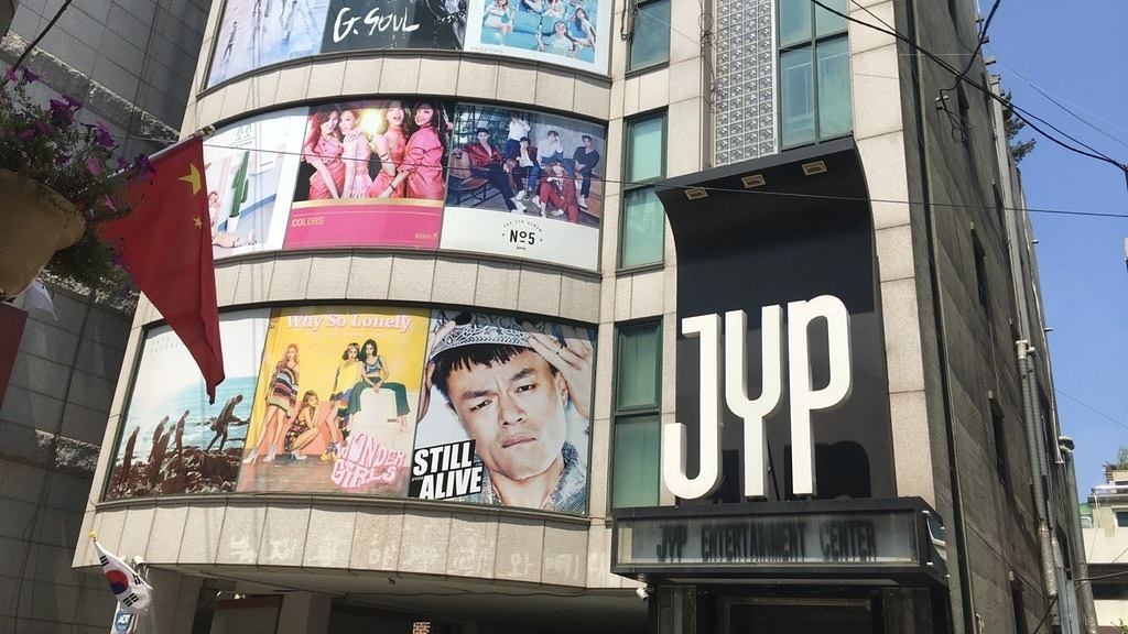 JYP Entertainment company building in Seoul with album cover displays on the facade — sasaeng fan explained