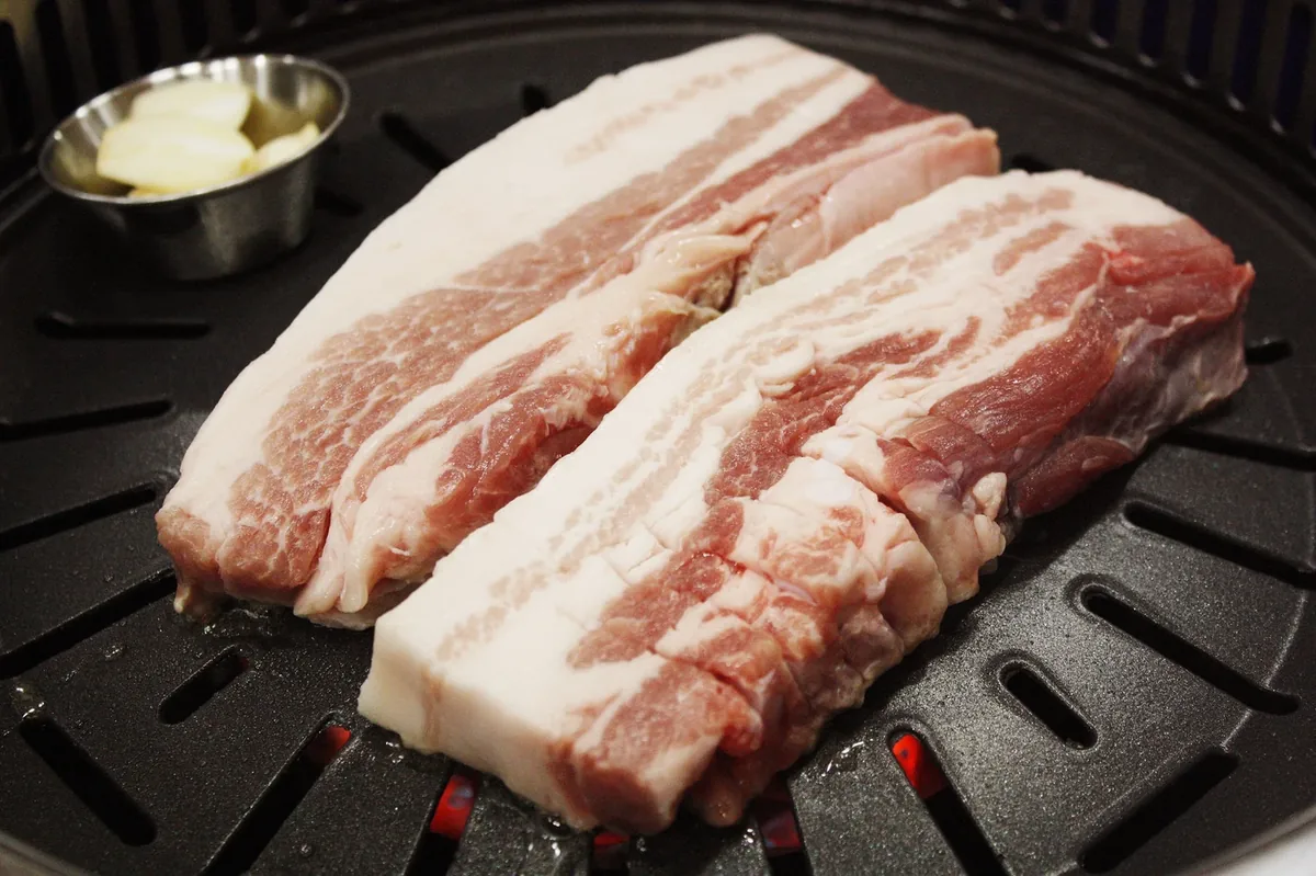 Samgyeopsal pork belly going on a Korean barbecue grill — bts grammy arirang